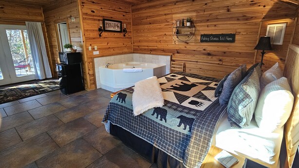 Een kamer in chaletstijl met een groot bed, een badkuip en een houten plafond.