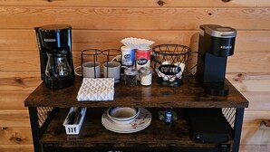 A coffee station with a coffee maker, cups, and a sign that says "Coffee keeps me going until it's time for wine." - Cabin-style private suite: king bed, jetted tub, kitchenette, Wi-Fi & private patio—near Beaver Lake & Eureka Springs. (Eureka Springs)