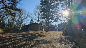 A cabin surrounded by tall trees and a clear sky. - Cabin-style private suite: king bed, jetted tub, kitchenette, Wi-Fi & private patio—near Beaver Lake & Eureka Springs. (Eureka Springs)