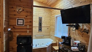 Interior de una cabaña de madera con baño, televisor y espacio para café.
