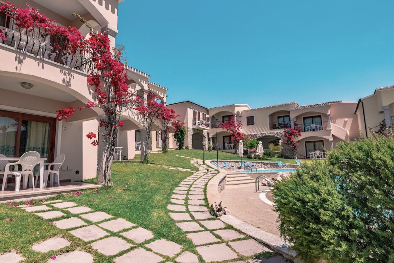 A courtyard with a swimming pool, outdoor seating, and a well-maintained lawn.