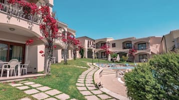A courtyard with a swimming pool, outdoor seating, and a well-maintained lawn.
