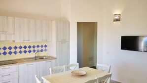 Una cocina moderna con armarios blancos, un salpicadero azul y amarillo, y un comedor con mesa y sillas.