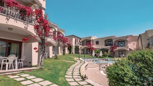 Un patio con piscina, mobiliario exterior y césped bien cuidado.