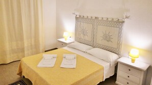 Una habitación de hotel con una cama, dos mesitas de noche, una lámpara y una cortina.