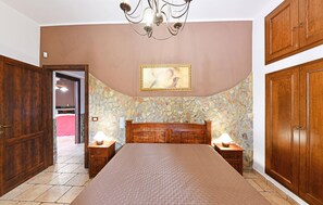 Ein Schlafzimmer mit einem großen Bett, einem Holzschrank und einer Steinwand.