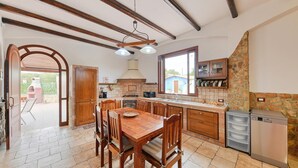 Une cuisine avec des meubles en bois, une table à manger et un lave-vaisselle encastré.