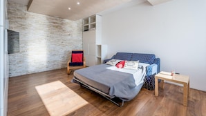 A modern bedroom with a loft bed, a wooden chair, a small table, and a brick wall. - Awesome home in Borso del Grappa with house a panoramic view (Borso del Grappa)