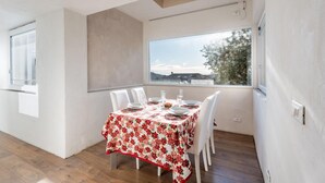 A dining area with a table set for four, large windows with a view, and a wooden floor. - Awesome home in Borso del Grappa with house a panoramic view (Borso del Grappa)