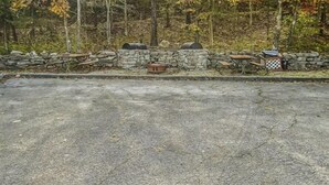 A paved area with a stone wall, a wooden bench, and a barbecue grill. - Standard Double Queen Room (Branson)