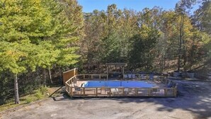 A rustic wooden deck with a raised platform and seating area, surrounded by dense forest. - Standard Double Queen Room (Branson)