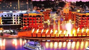A waterfront hotel with a central fountain, a boat dock, and a cityscape in the background. - Standard Double Queen Room (Branson)