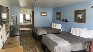A room with two beds, a desk, a mirror, and a dresser. - Standard Double Queen Room (Branson)