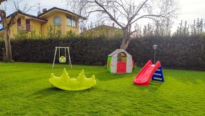 A grassy backyard with a swing set, a small playhouse, and a slide. - 1 bedroom cozy apartment in Massarosa (Massarosa)