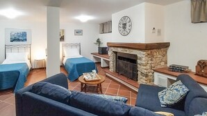 A cozy hotel room with two single beds, a stone fireplace, a sofa, and a small table with a tray of tea. - 1 bedroom cozy apartment in Massarosa (Massarosa)