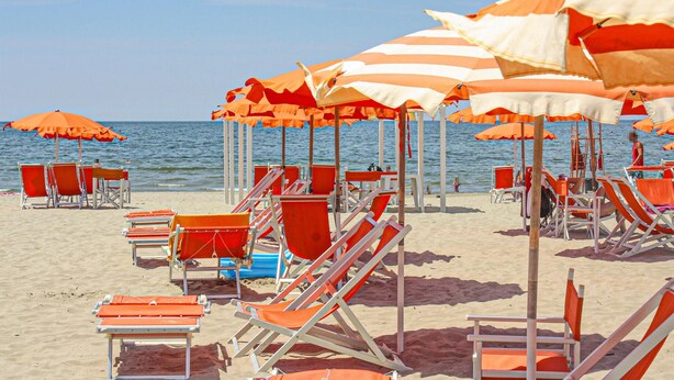 A beach with rows of orange and white striped umbrellas and red and white beach chairs. - 1 bedroom cozy apartment in Massarosa (Massarosa)