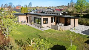 Ein modernes, zweistöckiges Haus mit einer großen Terrasse und einer einladenden Veranda.