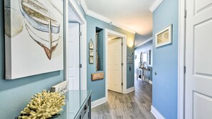 A hallway with teal walls, wooden flooring, and a glass display case with a coral. - Renovated oceanfront penthouse condo - direct beach access!  (Fort Walton Beach)