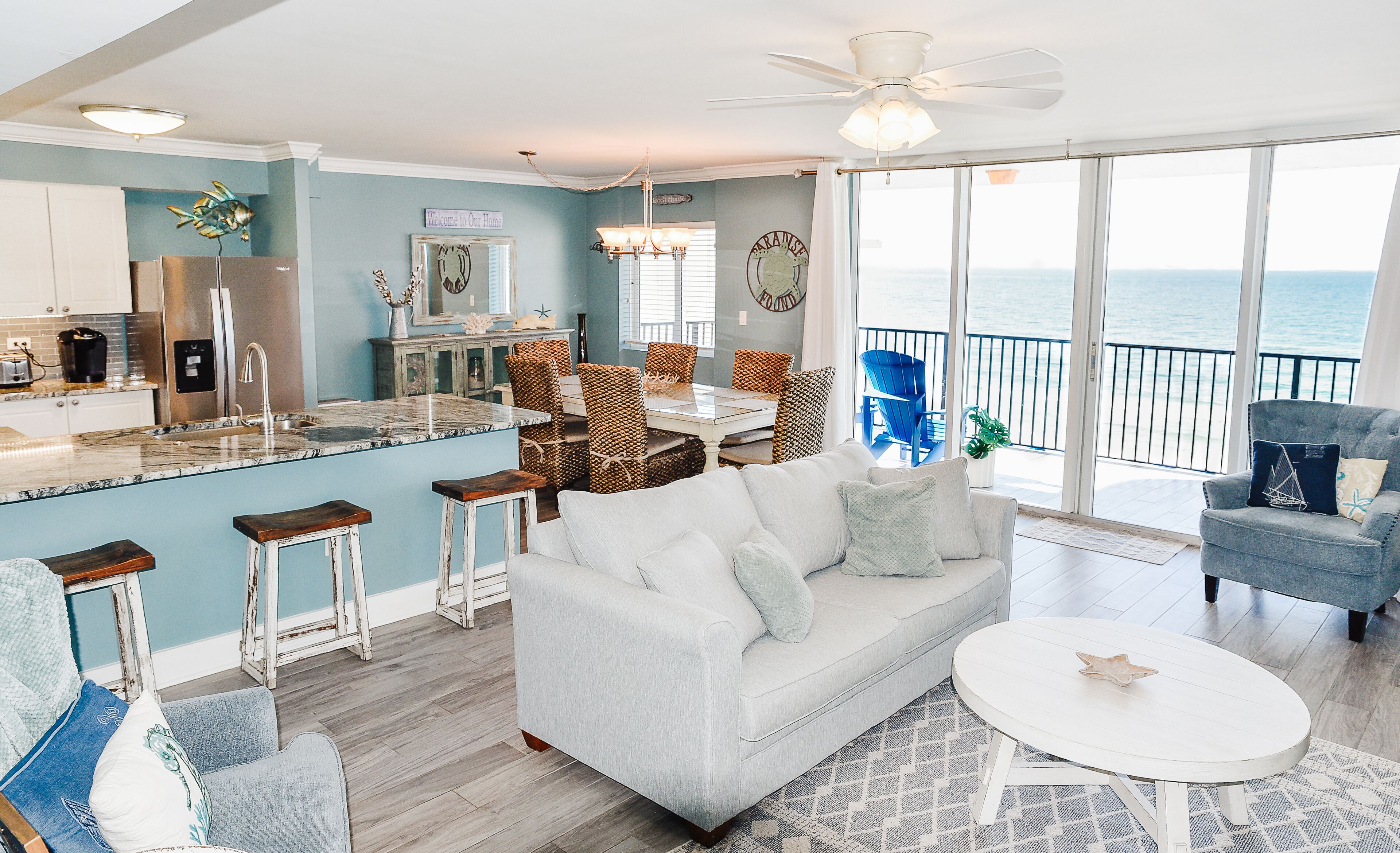 A spacious living area with a sofa, chairs, a dining table, and a kitchen area with a refrigerator and bar stools.