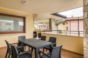 Un balcon avec une table et des chaises, une fenêtre et une vue sur les bâtiments.