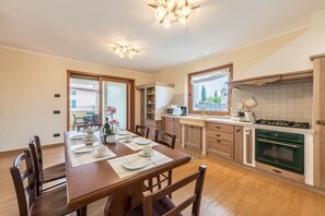 Une cuisine moderne avec des meubles en bois, un four vert et un coin repas avec une table dressée pour quatre personnes.