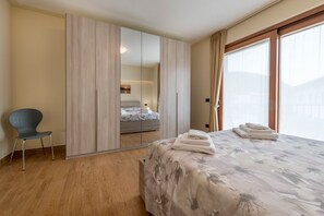 Une chambre à coucher avec un lit, une chaise, une armoire et une grande fenêtre.