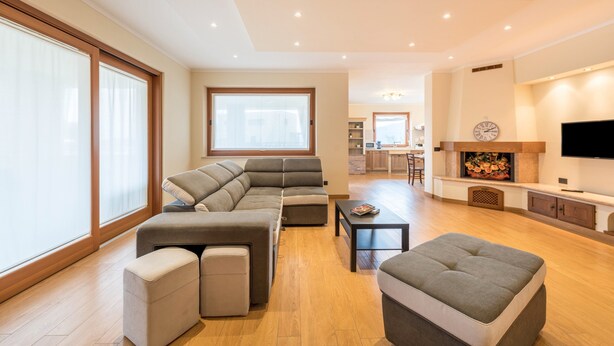 A spacious living room with a sectional sofa, ottomans, a coffee table, and a TV.