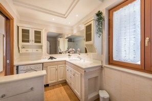 Une salle de bain compacte et bien éclairée, équipée d’un lavabo, d’un miroir et de toilettes.