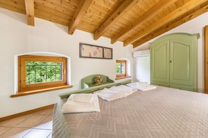 Ein Schlafzimmer mit einem Bett, zwei Fenstern, einem grünen Kleiderschrank und einer Holzbalkendecke.