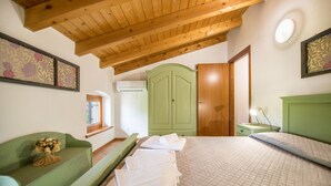 Een slaapkamer met een bed, een groene bank, een houten plafond en een groene garderobe.