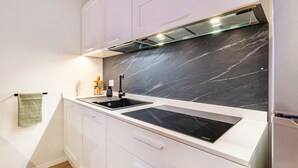 Una cocina moderna con armarios blancos, un salpicadero de mármol negro y una estufa integrada.