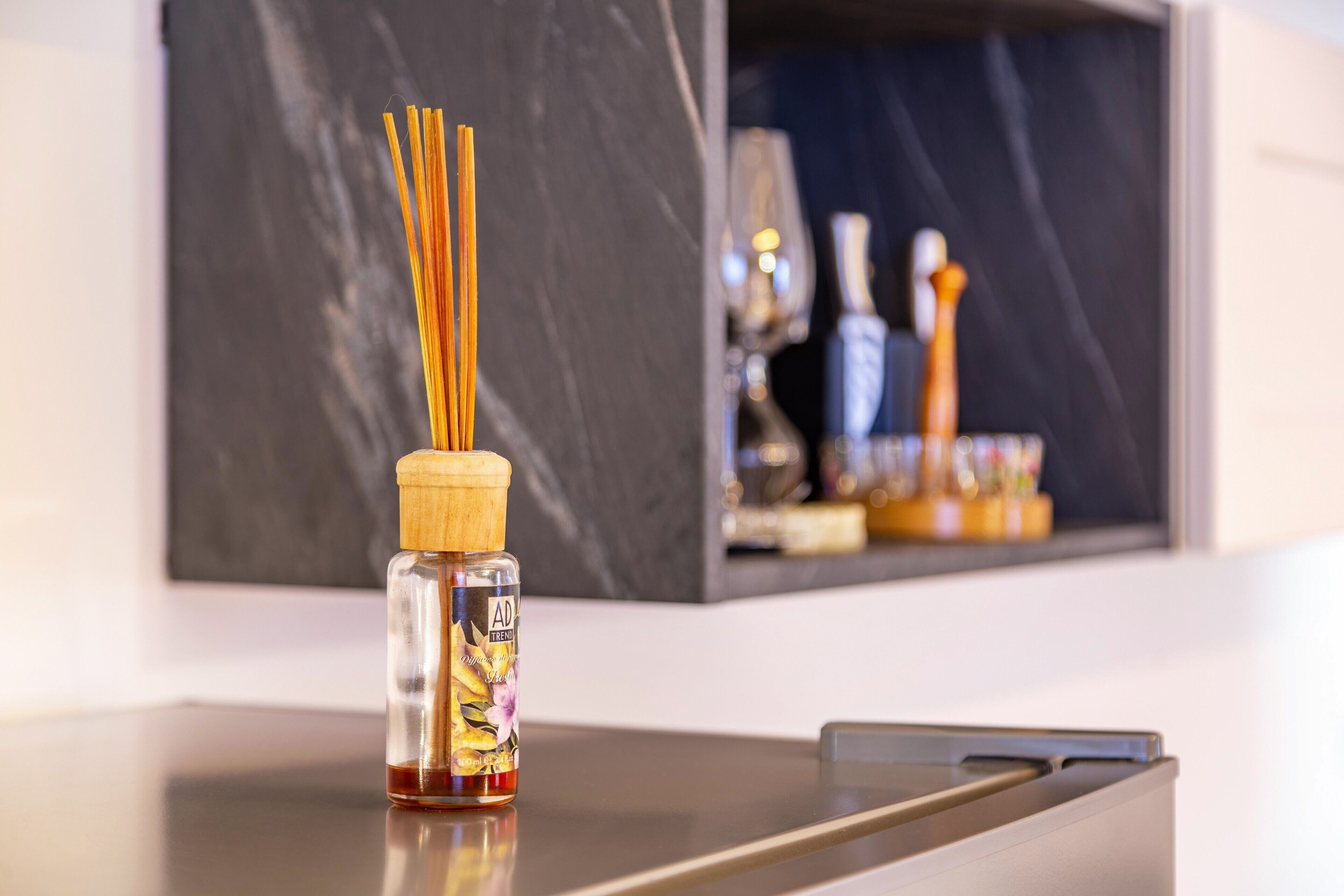 Una botella de AD Trend con tapa de madera y un diseño floral, sobre una superficie reflectante.