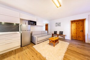 Una cucina moderna con mobili bianchi, frigorifero integrato e un tavolo da pranzo in legno con un tappeto morbido bianco.