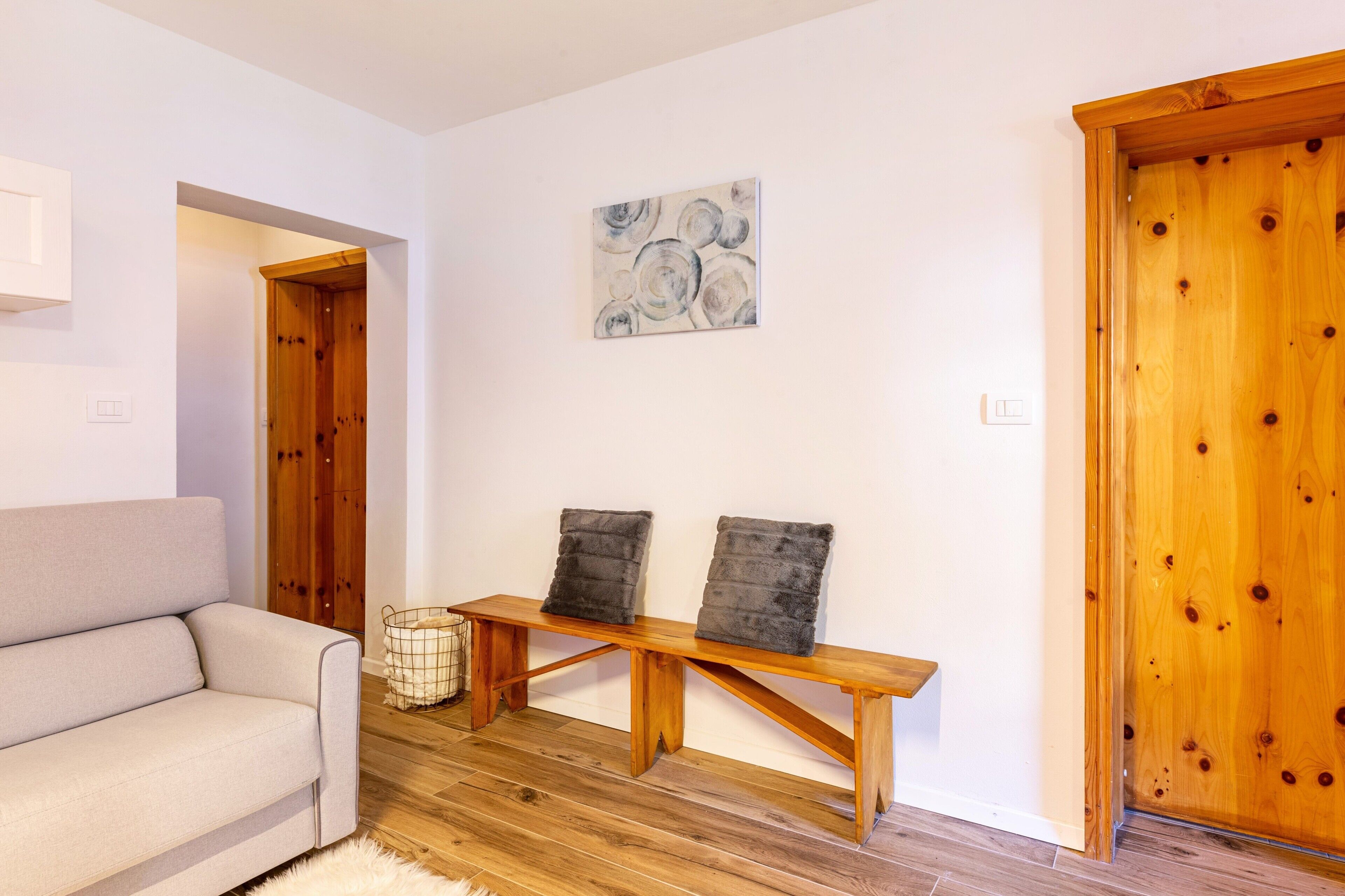 A room with a wooden bench, a sofa, and a wooden door.