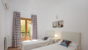 Une chambre d’hôtel avec deux lits, une fenêtre avec des rideaux à motifs, un radiateur et des œuvres d’art accrochées au mur.