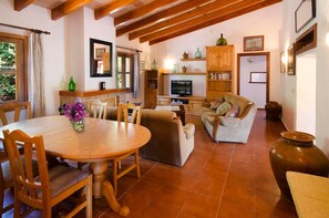 Una sala de estar acogedora con una mesa de comedor de madera, un sofá y un televisor.