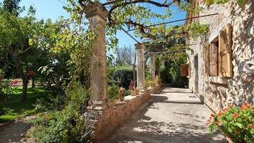 A stone building with a garden path leading to a covered area with columns.