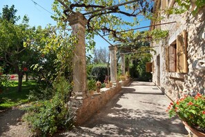 A stone building with a garden path leading to a covered area with columns.