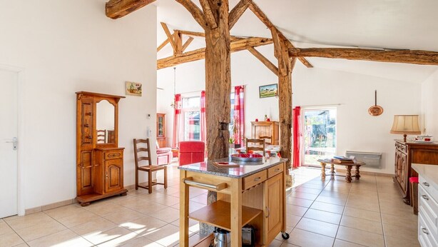 A spacious kitchen with a wooden table, chairs, and cabinets.
