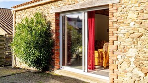 Un bâtiment en pierre avec une entrée en briques, une porte coulissante en verre et un pot de fleurs.
