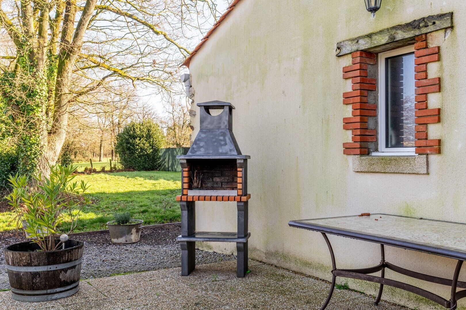 An outdoor barbecue grill, a table, and a potted plant.