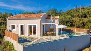 Una casa moderna con piscina, un patio cubierto y vistas de la vegetación circundante.