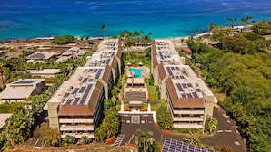 Een hotel met meerdere gebouwen, voorzien van zonnepanelen op het dak, een zwembad en uitzicht op de oceaan.