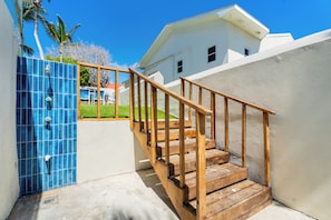 A wooden staircase leading to a white building with a blue tiled wall on the left.