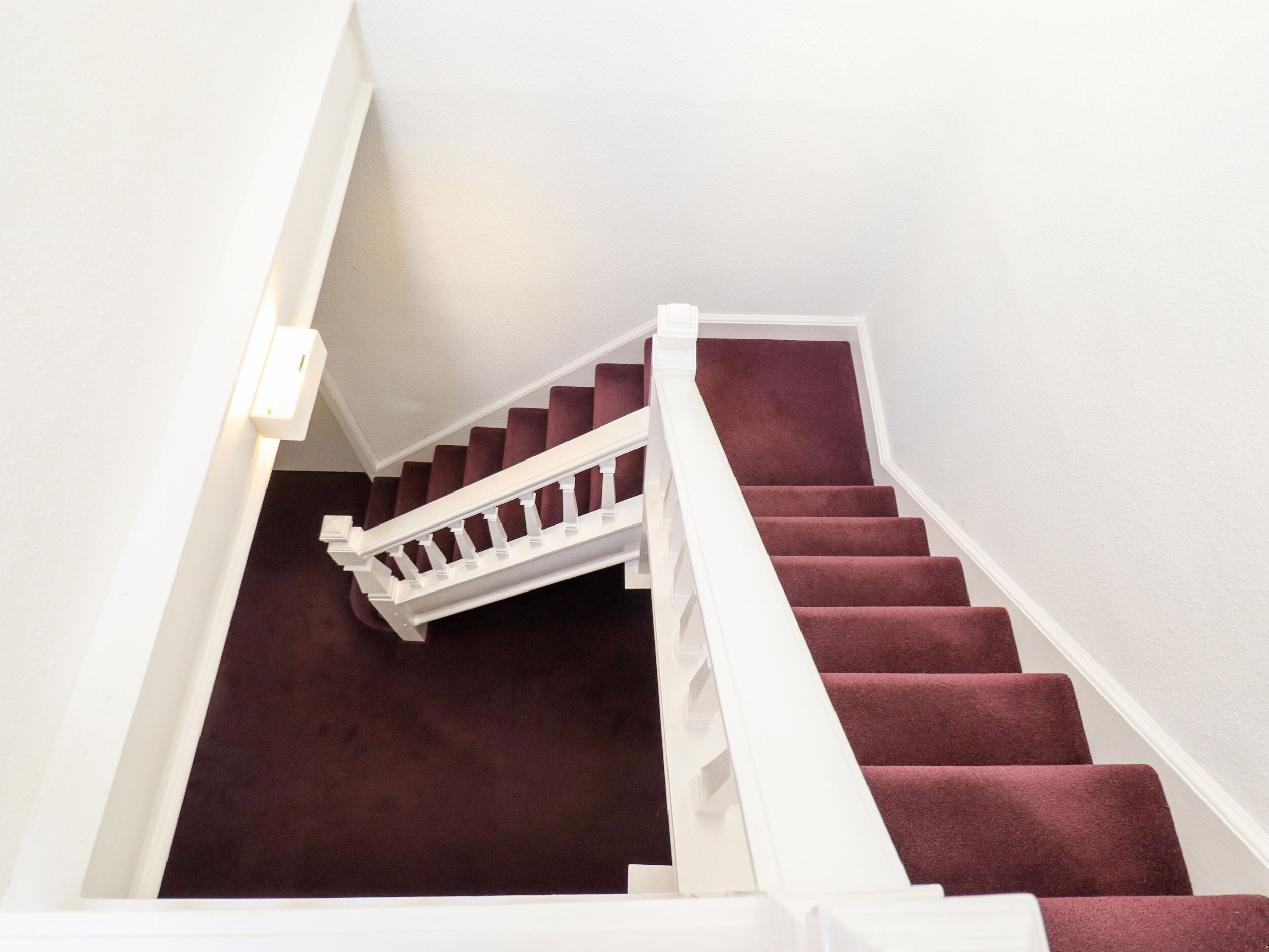 Eine Treppe mit weißen Geländern und einem dunklen Teppich.