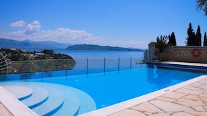 Una piscina con vistas claras al mar y montañas al fondo.