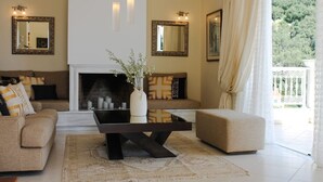 Una sala de estar con chimenea, sofás, una mesa de centro y dos espejos en la pared.