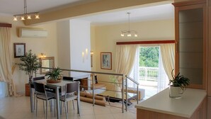Un comedor amplio con una lámpara moderna, una mesa de comedor con sillas, una escalera que conduce a un balcón y una zona de cocina con encimera y armarios.