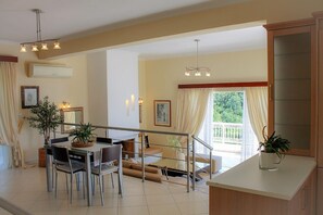 Un comedor amplio con una lámpara moderna, una mesa de comedor con sillas, una escalera que conduce a un balcón y una zona de cocina con encimera y armarios.