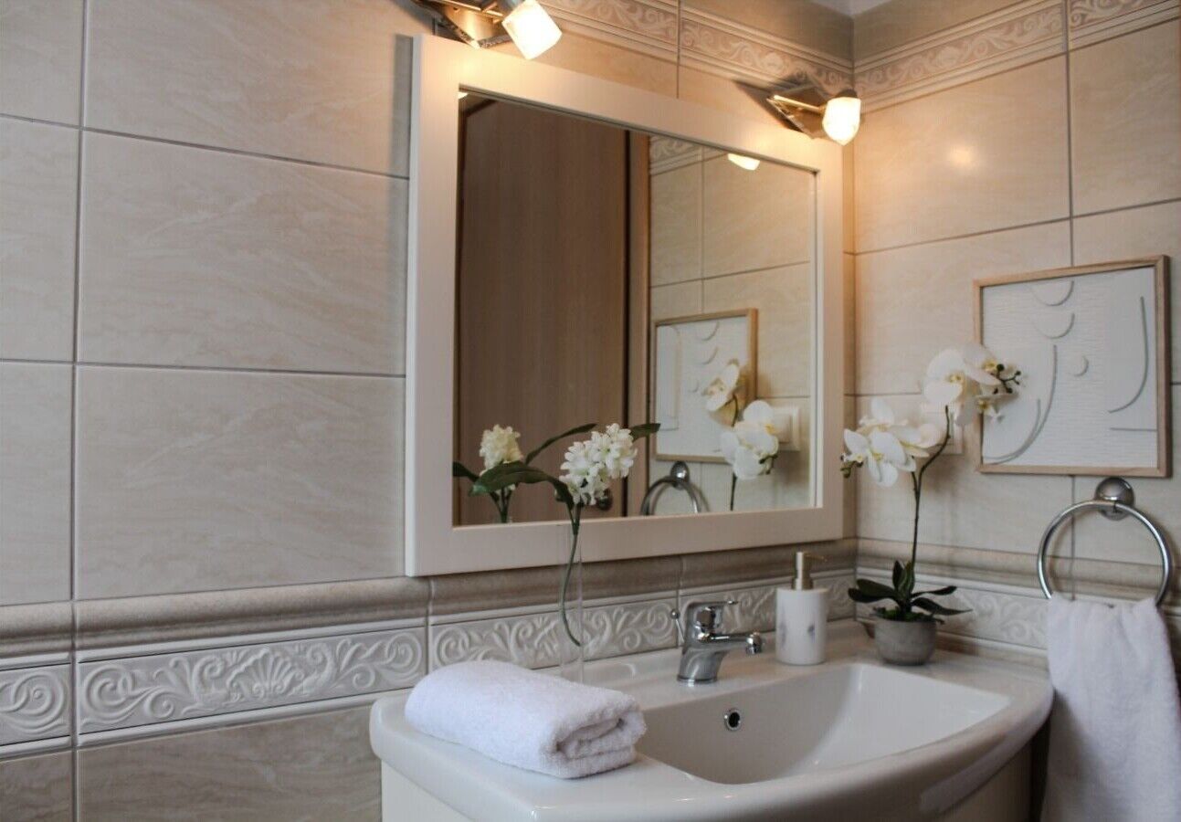 Un baño con lavamanos, espejo y azulejos decorativos.